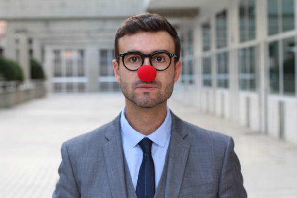 Businessman with a red clown nose isolated.