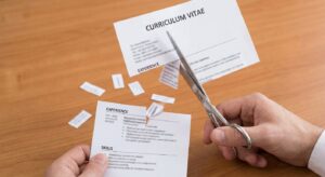 How to write a professional CV. A hand holding scissors, cutting out irrelevant sections or text from a document that looks like a CV. The cut pieces are falling away, leaving a more concise document.